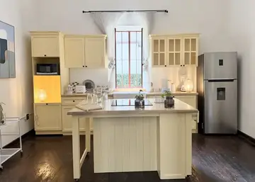 Cocina amarilla de Casa Popotla con isla central y una ventana vertical