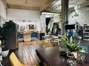 Cocina abierta de Loft 3 con isla de madera, comedor y muros de concreto aparente