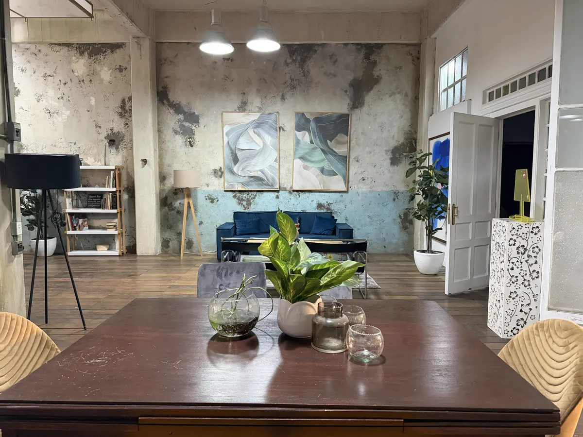 Sala de Loft 3 con sofá azul, plantas y paredes de textura industrial