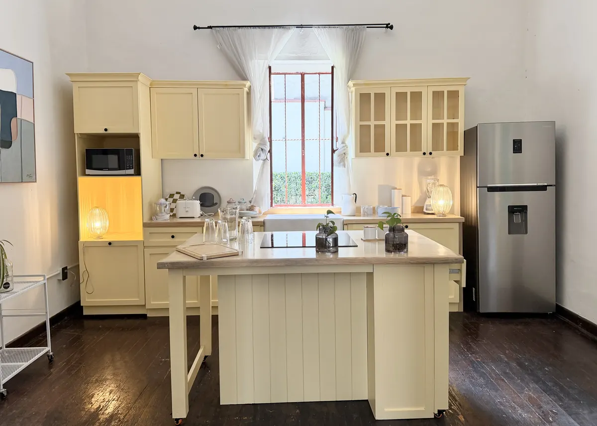 Cocina amarilla de Casa Popotla con isla central y una ventana vertical