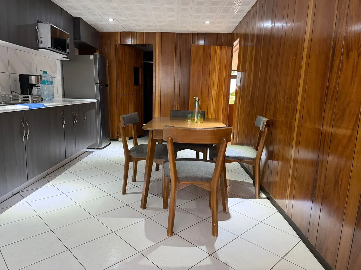 Comedor de Casa Santa Mónica con mesa de madera y revestimientos de madera junto a la cocina